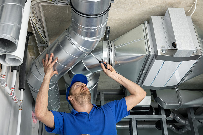 Commercial HVAC service repair man inspecting duct system